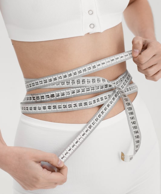 Девушка, измеряющая талию сантиметровой лентой